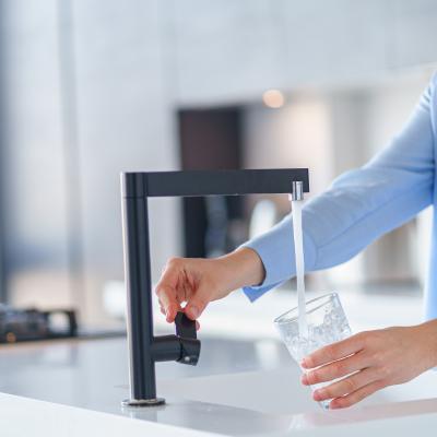 vrouw vult glas met water onder een kraan