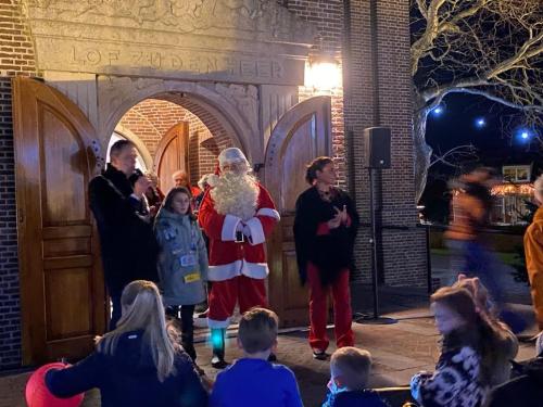 Burgemeester en kinderburgemeester samen met de kerstman voor de ingang van de kerk