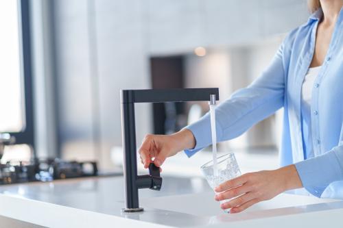 vrouw vult glas met water onder een kraan